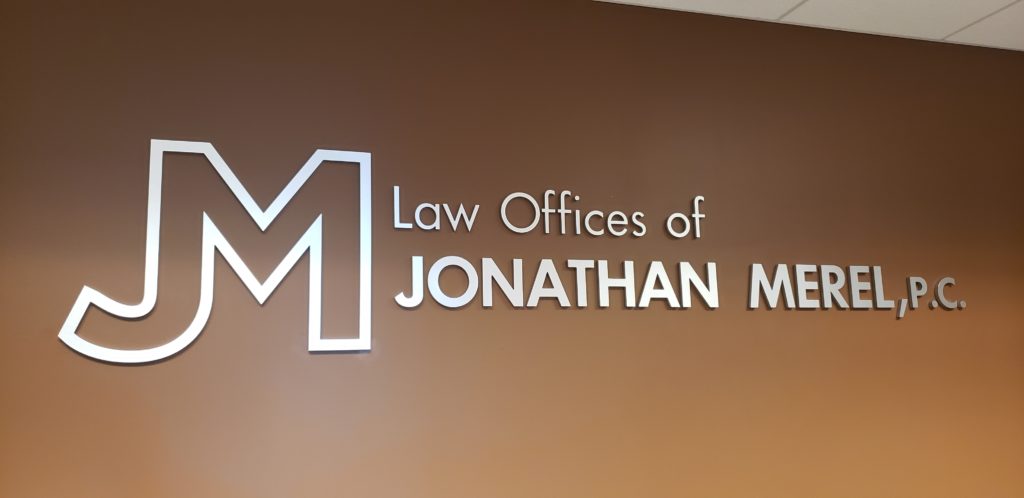 image of brushed metel lawyer sign on brown wall.